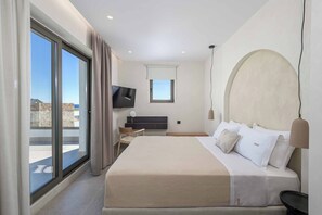 Ein modernes Hotelzimmer mit einem großen Bett, einem Fernseher, einem Schreibtisch und einem Balkon mit Aussicht.