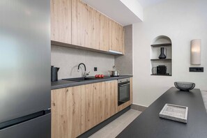 Eine moderne Küche mit Holzausstattung, einer schwarzen Arbeitsplatte, einem eingebauten Ofen und einem kleinen Regal mit einer Vase.