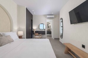Ein Hotelzimmer mit einem Bett, einem Schreibtisch, einem Sessel, einem Fernseher und einem Spiegel.