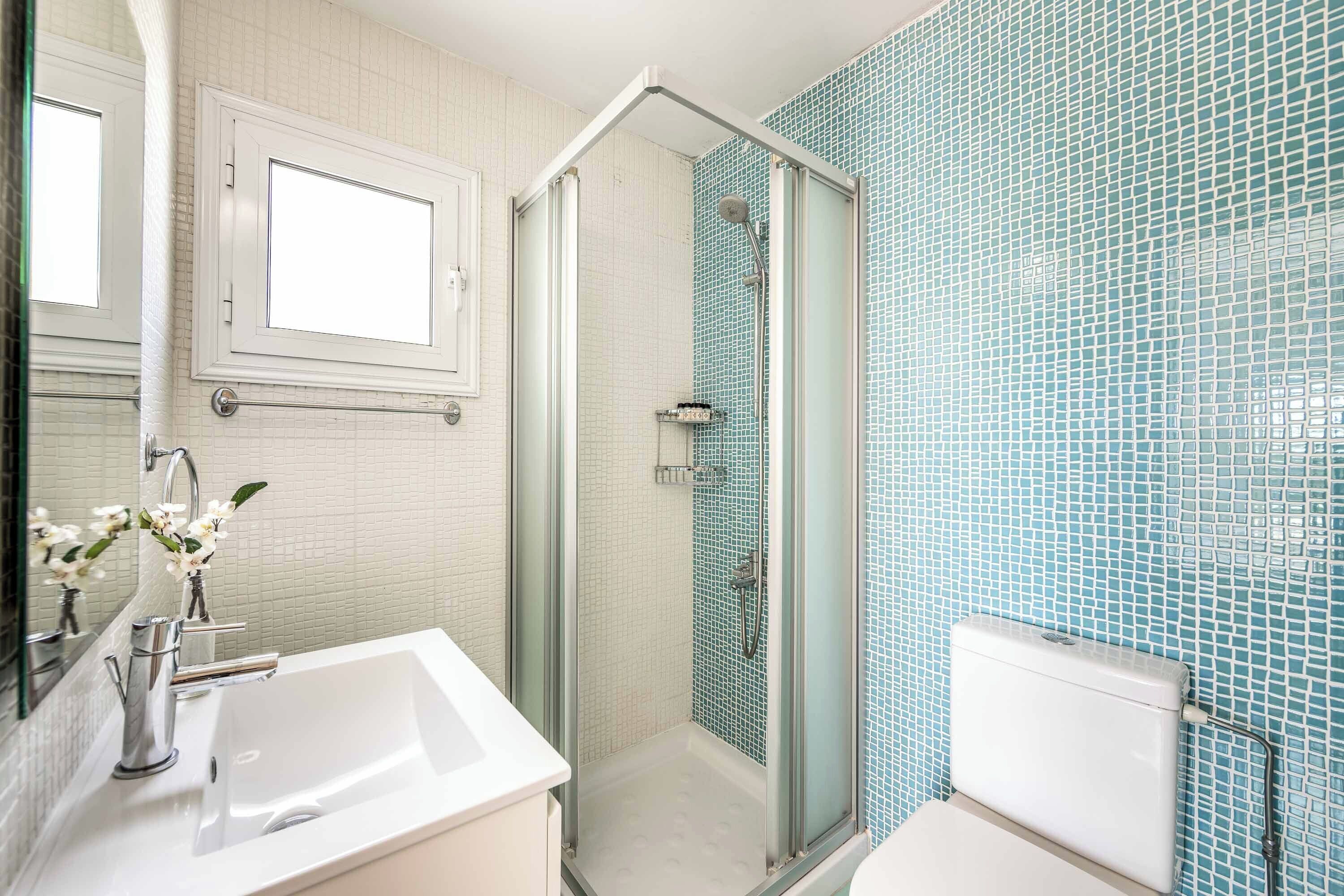 Ein Badezimmer mit einer Duschkabine, einem weißen Waschbecken und einer Toilette.