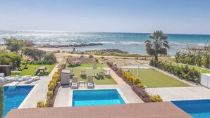 Ein Poolbereich mit Liegestühlen und Blick aufs Meer.