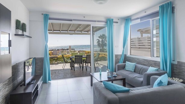 Ein modernes Wohnzimmer mit Fernseher, Sofa und Essbereich mit Blick auf den Ozean.