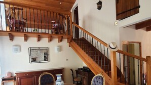 A dining area with a round table, chairs, and a staircase with wooden railings.