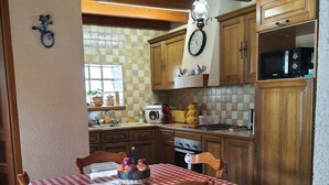 A kitchen with wooden cabinets, a red and white checkered tablecloth, and a clock on the wall.