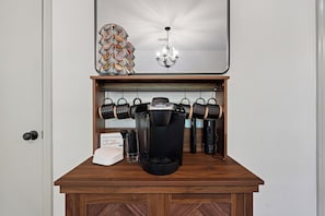 A coffee station with a Keurig machine, coffee cups, and a sign.