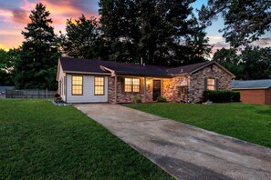 A two-story house with a brick exterior, a front porch, and a driveway leading to the garage.