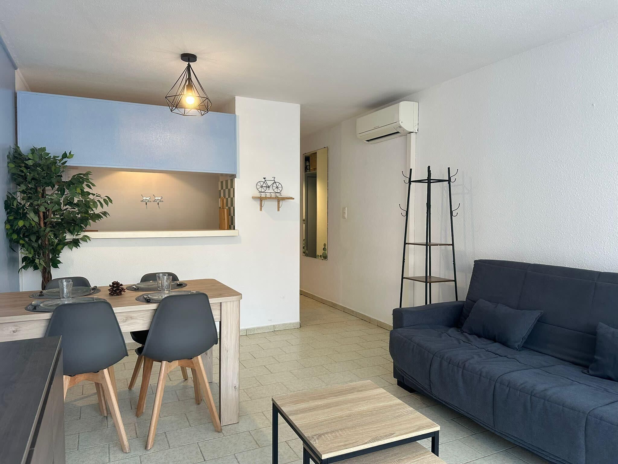 Un espacio habitable moderno con comedor, sofá, mesa de centro y una escalera contra la pared.