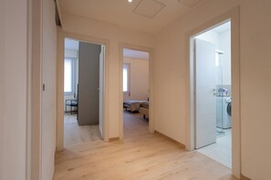 Ein Flur mit Holzboden, der zu einem Schlafzimmer mit Bett und Sessel führt.