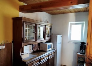 A kitchen with wooden cabinets, a microwave, a refrigerator, and a window.