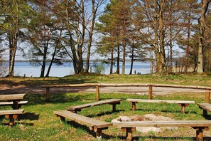 Un parque junto al lago con mesas de picnic y una valla de madera.