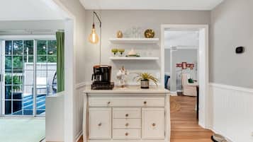 A kitchen with white cabinetry, a coffee machine, and a hanging light bulb.