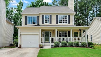 A two-story house with a front porch, garage, and a well-maintained lawn.