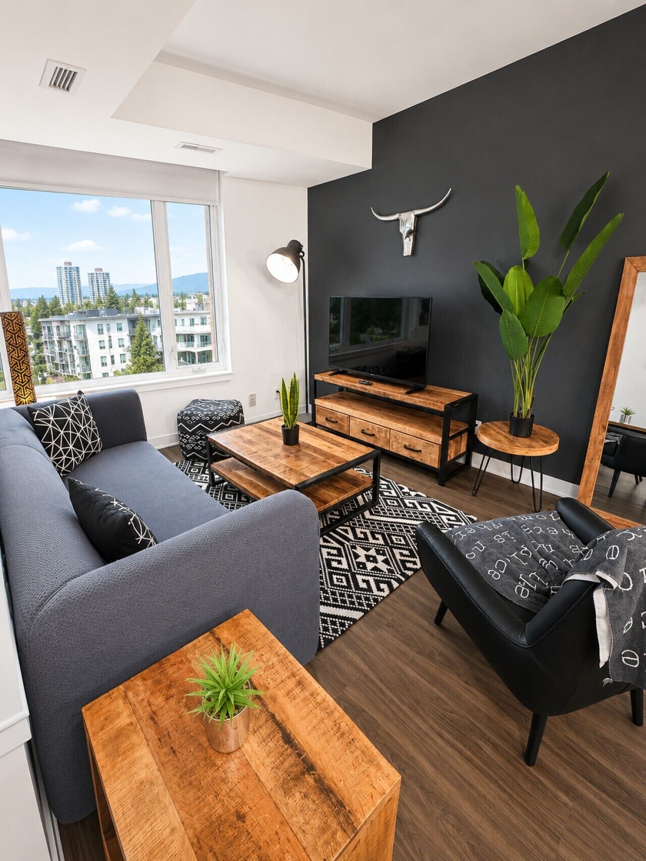A modern living room with a sofa, coffee table, TV, and a large plant.