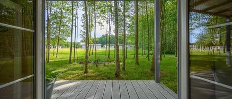 A covered outdoor area with a view of a grassy field and trees.