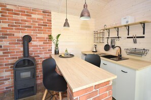 A kitchen with a brick wall, a wood-burning stove, a wooden countertop, and a hanging light fixture. - Comfortable Holiday Home no. 3B With a Fireplace (Darlowo)