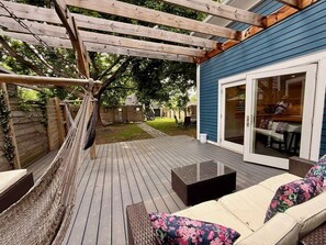 A deck with a hammock, outdoor furniture, and a sliding glass door leading to an interior space. - Heart of NE Arts District | 4BR | Deck + Skylights (Minneapolis)