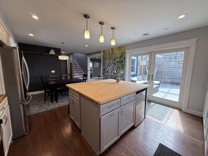 Une cuisine moderne dotée d’un îlot central, de planchers en bois et de luminaires suspendus.