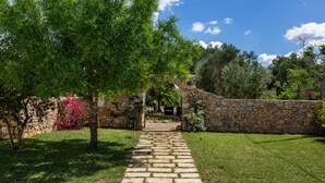 A stone pathway leading to a stone building with a garden and trees. - Symphony Sound By BarbarHouse (Sannicola)