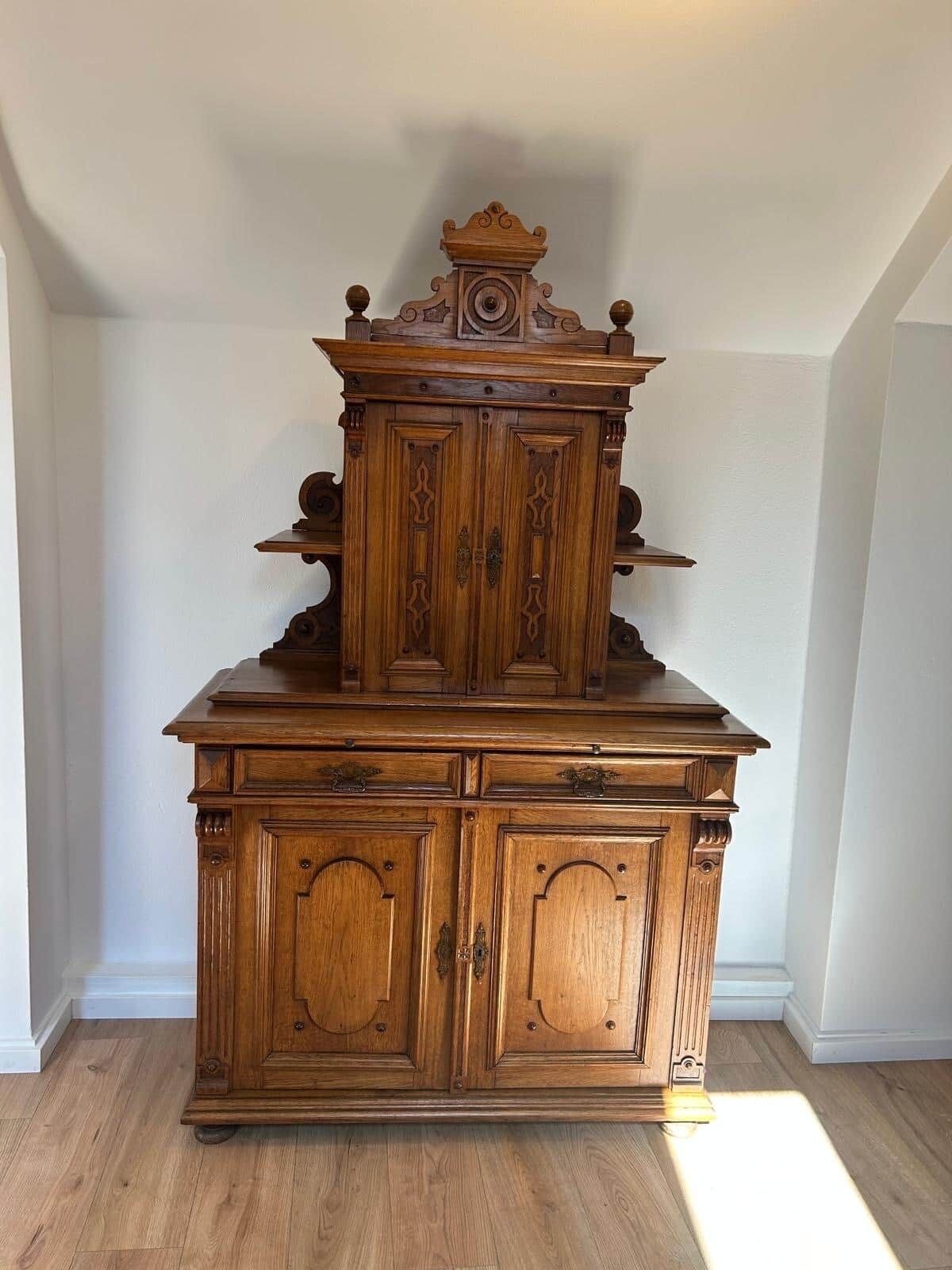 Een houten kast met decoratieve houtsnijwerken en een versierde bovenkant.