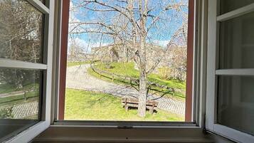 A room with a large window, a concrete floor, and a view of a tree and grassy area outside.