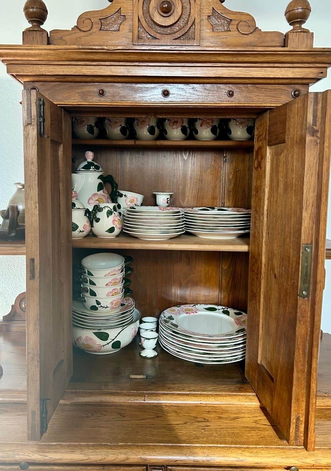 Ein Holzkabinett mit Regalen für Teller und Schüsseln.