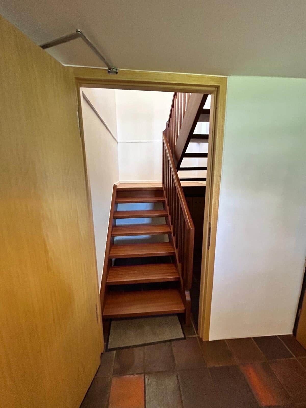 Una escalera de madera con barandilla, que conduce a una plataforma.