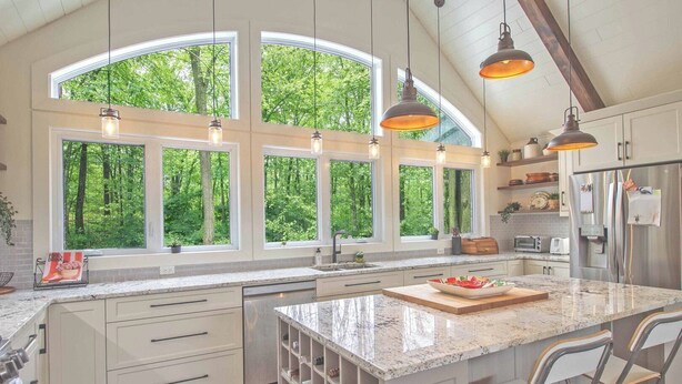 A kitchen with large windows, a central island, and modern appliances.