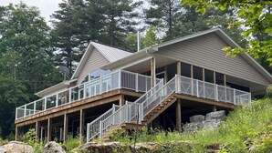 A two-story house with a balcony, wooden deck, and a staircase leading to the upper level.