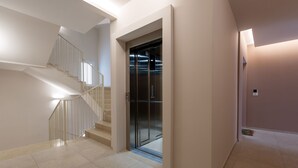 Un intérieur moderne avec un escalier, un ascenseur et un revêtement de sol carrelé.