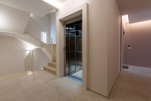 A modern interior with a staircase, elevator, and tiled flooring. - Dimora Melograno by BarbarHouse (Lecce)