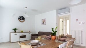 Un espace repas moderne avec une table en bois, des chaises, un meuble blanc et une horloge au mur.