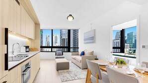 Eine moderne Wohnung mit Küche, Essbereich und Wohnraum, ausgestattet mit großen Fenstern und Blick auf die Stadt.