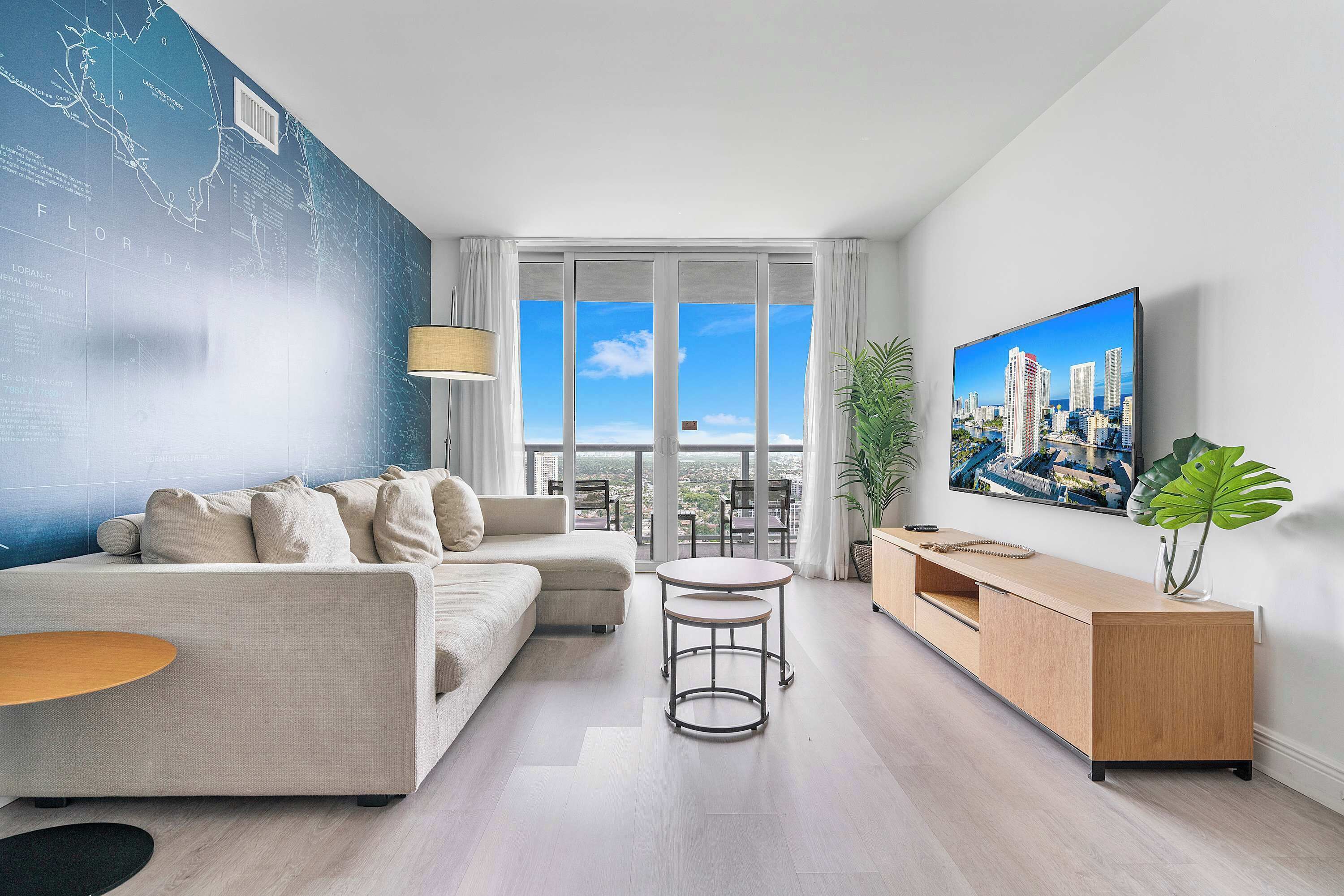 A modern living room with a sofa, a coffee table, a TV, and a cityscape painting.