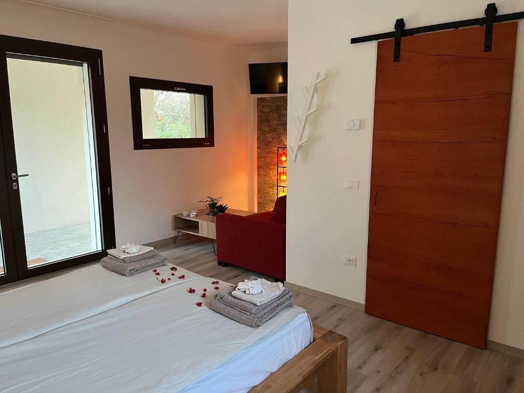 Un dormitorio con una cama, una puerta corredera, una silla roja y una pequeña mesa con una planta.