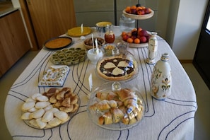Pöydällä on monenlaista syötävää, kuten leivonnaisia, piirakoita ja hedelmiä.