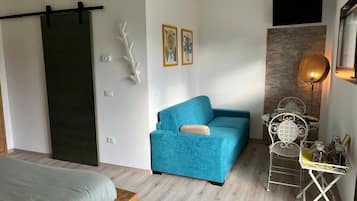 Chambre Quadruple Deluxe, plusieurs lits, fumeurs, vue parc | Coin séjour | TV connectée de 45 cm avec chaînes par câble