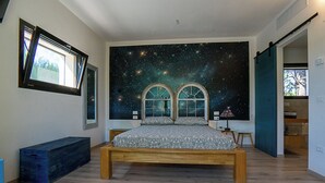 Un dormitorio con un mural de noche estrellada, una cama de madera y un banco.