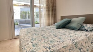 Ein Schlafzimmer mit Bett, einer Glasschiebetür zu einem Balkon und einem Kopfteil.