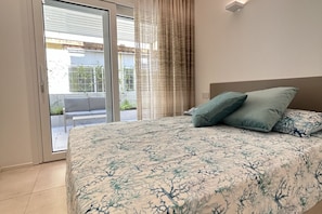 Ein Schlafzimmer mit Bett, einer Glasschiebetür zu einem Balkon und einem Kopfteil.