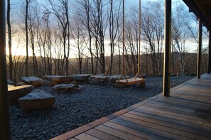 Eine Holzterrasse mit einer Schaukel, umgeben von Steinen und Bäumen.