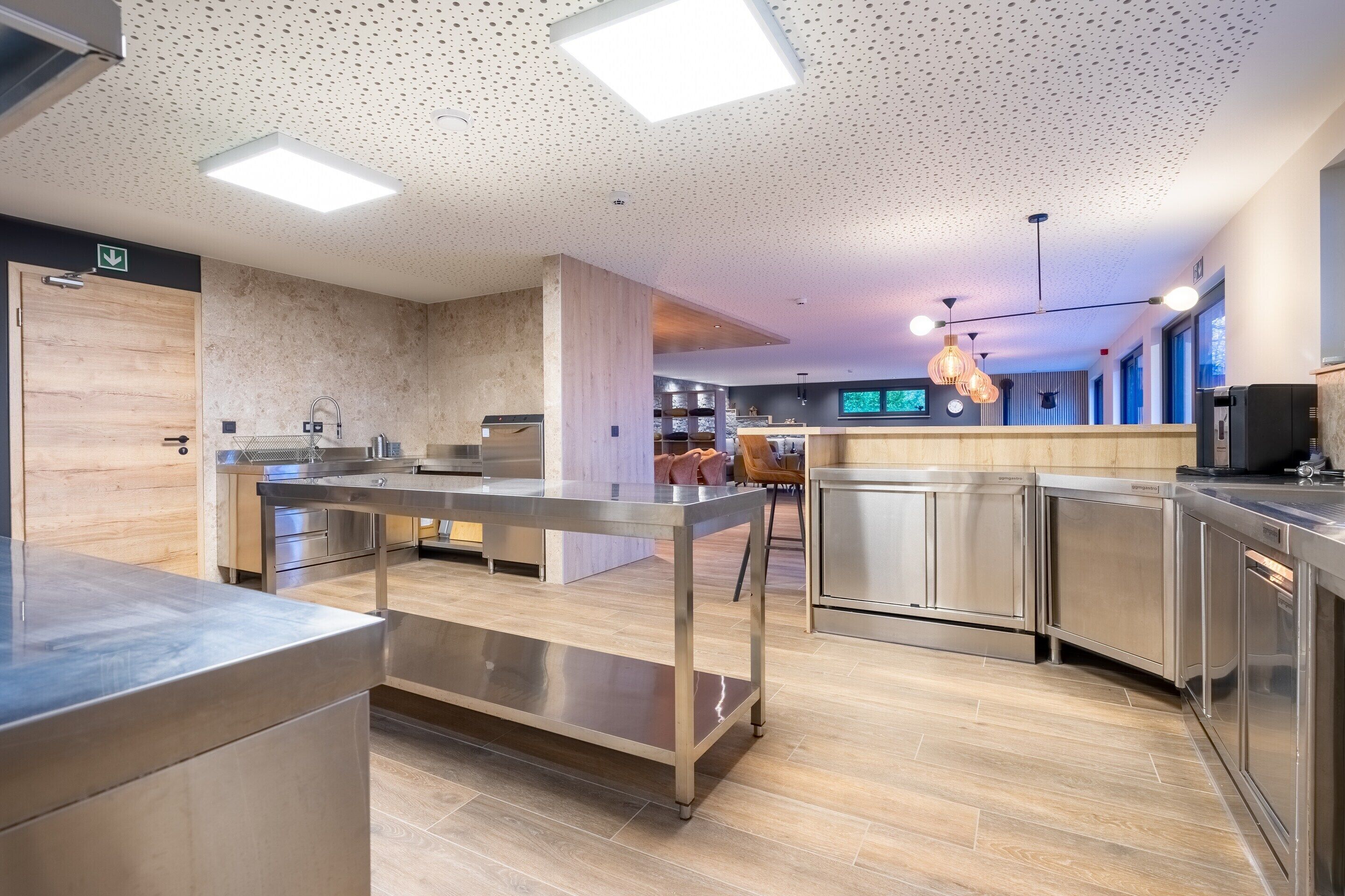 A modern kitchen with stainless steel appliances, a central island, and a seating area with chairs.