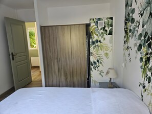 Una camera da letto con un letto, un armadio, una parete con carta da parati floreale e una porta che dà su un'altra stanza.