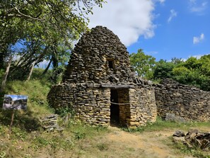 A stone structure with a doorway, surrounded by greenery and a clear sky. - Gîte Le Chalet in Vergt Between Périgueux and Bergerac (Vergt)