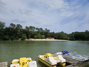 A calm lake with boats docked at the pier, surrounded by trees and a small building. - Gîte Le Chalet in Vergt Between Périgueux and Bergerac (Vergt)