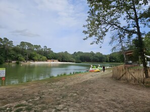 A lakeside area with swan-shaped boats, a wooden fence, and a small building. - Gîte Le Chalet in Vergt Between Périgueux and Bergerac (Vergt)