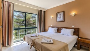 Ein Hotelzimmer mit zwei Betten, einem Balkon und einem großen Fenster.