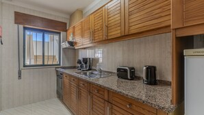 Eine Küche mit Holdekor-Schränken, einer Granit Arbeitsplatte, einem eingebauten Backofen, einer Kaffeemaschine, einem Toaster und einem Wasserkocher.