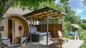 Uma cabana de madeira com banheira de hidromassagem, um alpendre coberto e um deck de madeira.