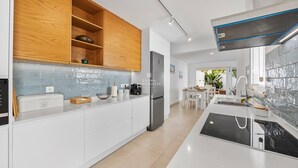 Et moderne køkken med hvide skabe, et rustfrit stål køleskab, en indbygget ovn og et backsplash med blå fliser.