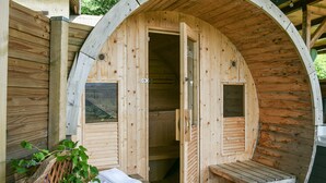 Una sauna de madera con techo abovedado, un banco y un ventanal pequeño.